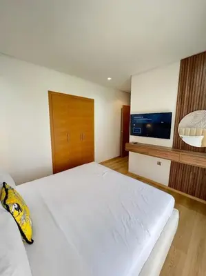 a bedroom with a large white bed and a flat screen tv at Appartement moderne au Golf in Marrakech