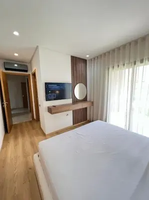 a bedroom with a white bed and a television at Appartement moderne au Golf in Marrakech