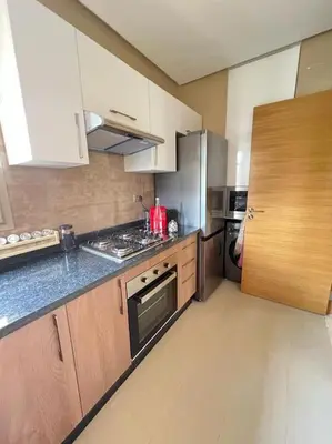 a kitchen with wooden cabinets and a stove top oven at Appartement moderne au Golf in Marrakech