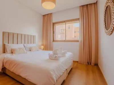 a bedroom with a large white bed with a window at Magnifique appartement 3 chambres à Prestigia in Marrakech