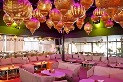 a restaurant with pink couches and colorful chandeliers at 555 Hotel Clubbing Adults Only in Marrakech