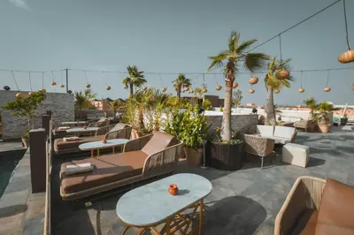 a patio with couches and tables and palm trees at 555 Hotel Clubbing Adults Only in Marrakech