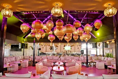 a room with pink chairs and tables and chandeliers at 555 Hotel Clubbing Adults Only in Marrakech