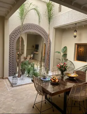 a living room with a table and chairs and palm trees at Private Riad 4 Bedrooms With Free Breakfast and Heated Plunge Pool in Marrakech