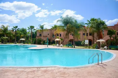 a large swimming pool in a resort with palm trees at Oasis de l'Atlas by Golf Resort in Marrakech
