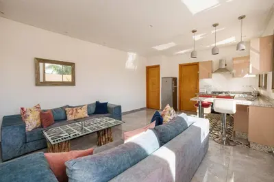 a living room with blue couches and a kitchen at le petit dar alwalidine in Marrakech