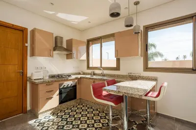 a kitchen with a table and red chairs at le petit dar alwalidine in Marrakech