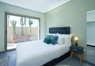 a bedroom with a white bed and a window with cactus at le petit dar alwalidine in Marrakech