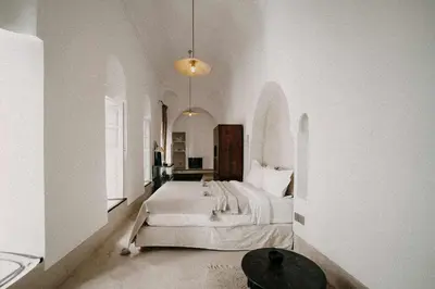 a white bedroom with a large bed and a table at Riad KRÈME in Marrakech