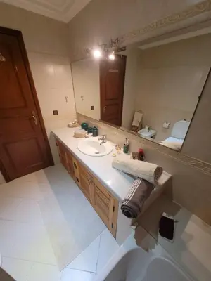 a bathroom with a sink and a large mirror at MELBARI Cosy-Appart in Marrakech