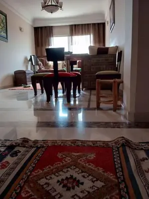 a living room with a table and a rug at Le Fairouz Appartement Haut Standing centre ville Piscine in Marrakech