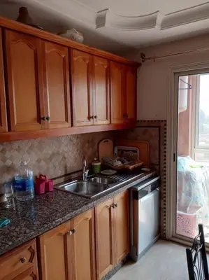 a kitchen with wooden cabinets and a sink at Le Fairouz Appartement Haut Standing centre ville Piscine in Marrakech