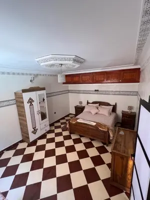 a bedroom with a bed and a checkered floor at Charmant appartement spacieux avec cour fleurie et Hammam à Targa Marrakech in Marrakech