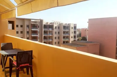 a table and chairs on a balcony with a view of buildings at Appartement haut standing plein centre gare in Marrakech