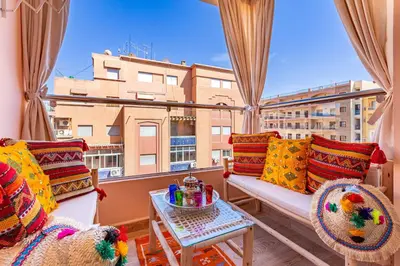 a balcony with a couch and chairs and a window at Magnifique appartement unique et central! in Marrakech