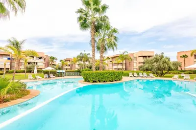 a large swimming pool with palm trees and buildings at Appartement luxe Prestige Opale Golf in Marrakech