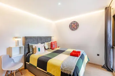 a bedroom with a bed and a chair at Appartement luxe Prestige Opale Golf in Marrakech