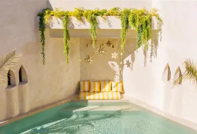 a swimming pool in a room with a yellow chair at Suites & Spa - Riad XO in Marrakech