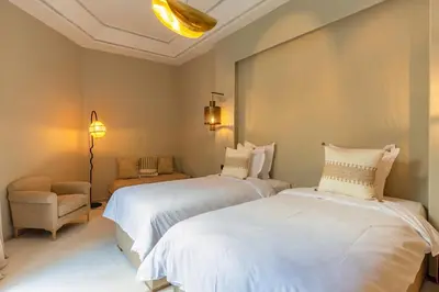 a bedroom with two beds and a chair and lights at Suites & Spa - Riad XO in Marrakech