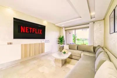 a living room with a couch and a tv at Vue Montagnes, Golf et Piscine, Luxe à Marrakech in Marrakech