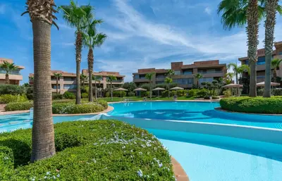 a swimming pool with palm trees in front of a resort at Vue Montagnes, Golf et Piscine, Luxe à Marrakech in Marrakech