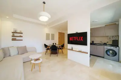 a living room with a white couch and a kitchen at Appartement NOVA Noria in Marrakech