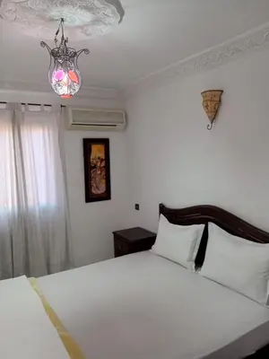 a bedroom with a large white bed with a chandelier at Riad Selma résidence face Médina avec Piscines in Marrakech