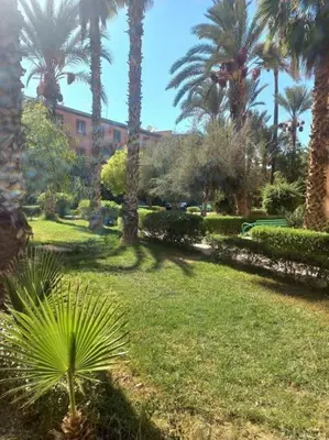 a park with palm trees and a building in the background at Riad Selma résidence face Médina avec Piscines in Marrakech