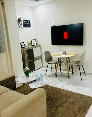 a living room with two tables and a tv on the wall at Charmant appartement en plein centre ville gueliz in Marrakech