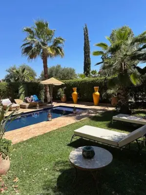 a backyard with a swimming pool and palm trees at Villa LES LAURIERS, 4 suites, piscine privée, petit déjeuner compris in Marrakech