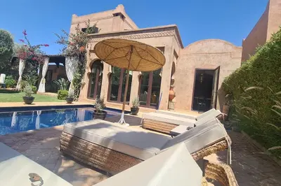 a chair with an umbrella next to a pool at Villa LES LAURIERS, 4 suites, piscine privée, petit déjeuner compris in Marrakech