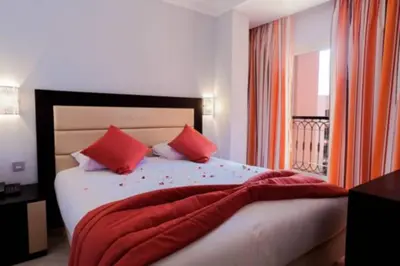 a bedroom with a large bed with red pillows at Palm Appart Hôtel Marrakech in Marrakech