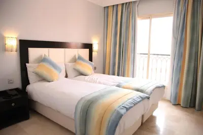 a bedroom with a large bed with a large window at Palm Appart Hôtel Marrakech in Marrakech