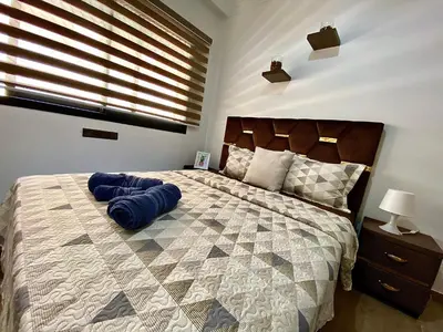 a bedroom with a large bed with a blue pillow on it at apparte 2 chambres luxe en face la gare gueliz in Marrakech