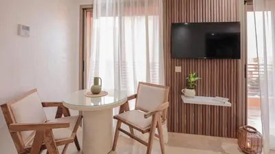 a living room with a table and chairs and a television at Piscine chauffée - Sauna - Hammam - Appart Coeur de Gueliz in Marrakech