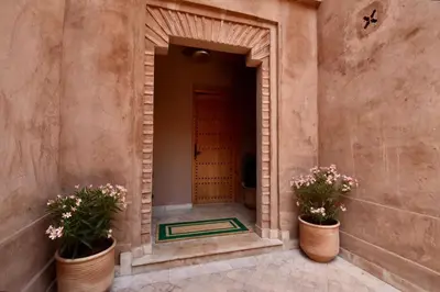 an entrance to a building with two potted plants at Modern Garden-Level Apartment with Pool & Jacuzzi in Marrakech
