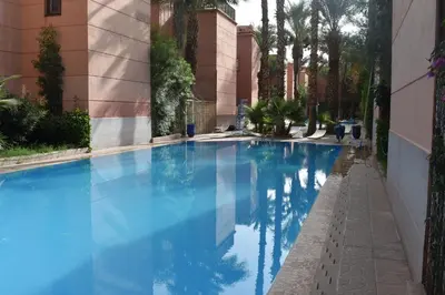 a blue swimming pool in a building with palm trees at Riad butterfly Marrakech in Marrakech