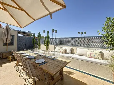 a wooden table with chairs and a couch on a patio at Riad Azrak in Marrakech