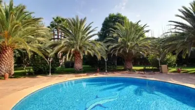 a large blue swimming pool with palm trees in the background at Villa Dauphin in Marrakech