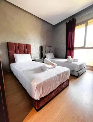 a bedroom with two beds and a large window at Prestigious Apartment in Marrakech