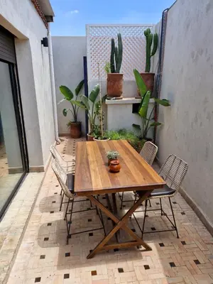 a wooden table and chairs on a patio with plants at Luxueux Duplex rooftop en plein cœur de Majorelle in Marrakech