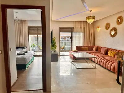 a living room with a couch and a bed at PEARL GARDEN Luxueux Studio Chic Piscine Terrasse Netflix IPTV Parking in Marrakech