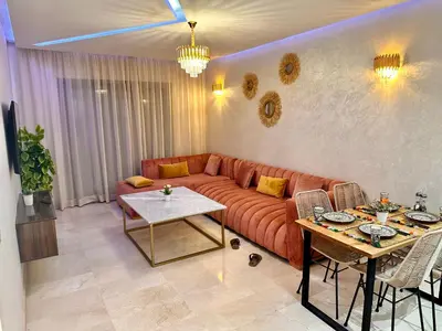 a living room with a couch and a table at PEARL GARDEN Luxueux Studio Chic Piscine Terrasse Netflix IPTV Parking in Marrakech