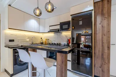 a kitchen with a counter with white chairs in it at Luxurious City Apartment in Marrakech