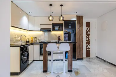 a kitchen with a counter and two white stools at Luxurious City Apartment in Marrakech