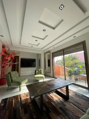 a living room with a table and chairs and a television at Bel Appartement Hivernage-Gueliz 2 chambres in Marrakech