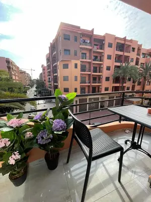a balcony with a table and chairs and flowers at Bel Appartement Hivernage-Gueliz 2 chambres in Marrakech