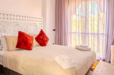 a bedroom with a bed with red pillows and a window at Luxury Villa with Pool, Garden & Gated Security in Marrakech