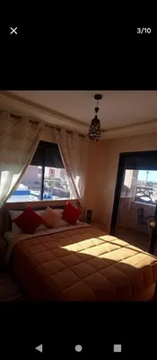 a bedroom with a large bed and two windows at Magnifique appartement in Marrakech