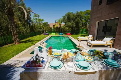 a table with plates of food next to a swimming pool at Villa oasis private pool secure complex in Marrakech